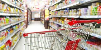Massive Recall STUNS Supermarkets Empty shopping cart in grocery store aisle.