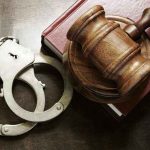 Infant Abandoned—Exec Couple Under Fire! Handcuffs beside a gavel on a book