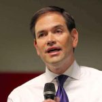 Rubio BETRAYS US Informants in Shocking Deal Man in white shirt speaking into a microphone.