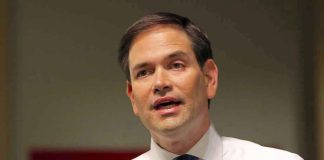 Man in white shirt speaking into a microphone.