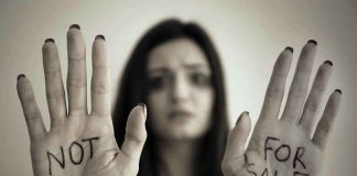 Handcuffed woman shows NOT FOR SALE on her palms