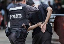 Police officer arrests handcuffed person