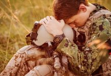 Soldier sitting leaning head on helmet