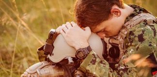 Soldier sitting leaning head on helmet