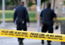 Police officers walking past caution tape at a crime scene