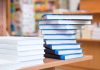 A stack of neatly arranged books on a wooden table in a bookstore