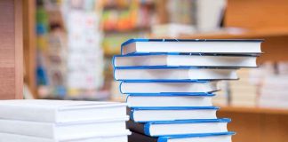 A stack of neatly arranged books on a wooden table in a bookstore