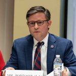 GOP Warns of Extended Shutdown Crisis A public official speaking at a meeting with a nameplate in front of him