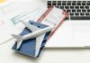 A model airplane on a blue passport next to a laptop and boarding pass