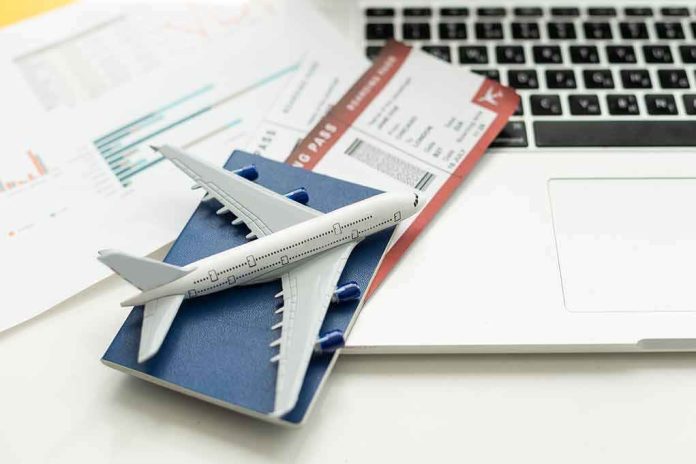 shutterstock_2336014405.jpg A model airplane on a blue passport next to a laptop and boarding pass