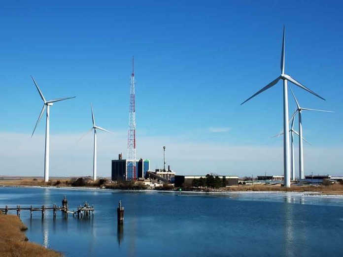 shutterstock_2718216.jpg Wind turbines and a communication tower near a body of water under a clear blue sky