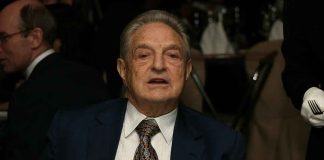 Elderly man in a suit sitting at a dining table during a formal event