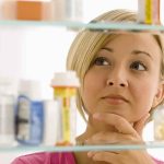 AMR Threatens Millions: Could This Be the Next Plague? A woman thoughtfully looking at a medicine cabinet filled with various medications