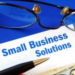 $550 Million Minority Front SCHEME Uncovered Close up of glasses and a pen resting on a document titled Small Business Solutions