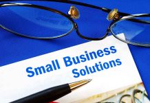 Close up of glasses and a pen resting on a document titled Small Business Solutions