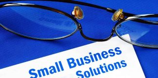 Close up of glasses and a pen resting on a document titled Small Business Solutions