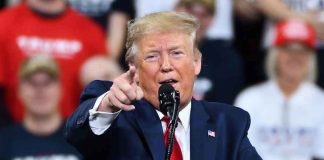 Man in suit pointing speaking at a rally