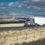Court BLOCKS Trump’s CDL Rule Truck driving on rural highway near river and mountains