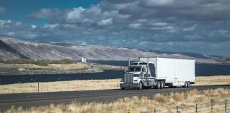 Truck driving on rural highway near river and mountains