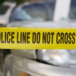 Yellow police tape in front of a car