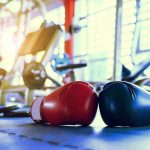 Boxing gloves on gym floor with equipment