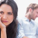 A woman looking concerned while a man appears distressed in the background