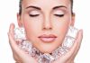 A woman with closed eyes holding ice cubes against her face