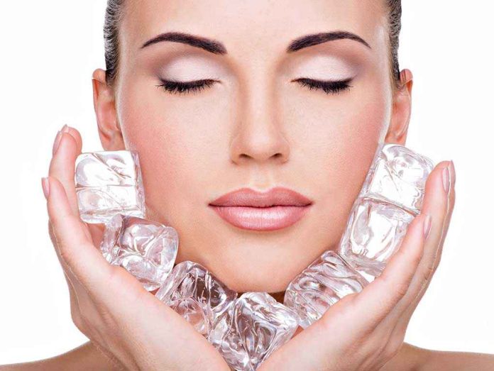 A woman with closed eyes holding ice cubes against her face