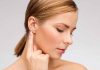 Profile view of a woman gently touching her ear with a thoughtful expression