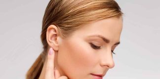 Profile view of a woman gently touching her ear with a thoughtful expression