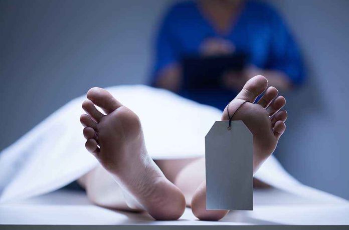 shutterstock_210811072.jpg A deceased body on a table with a tag on the foot and a medical professional in the background
