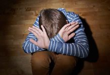 A child sitting on the floor with their hands covering their face, expressing distress
