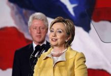 Epstein Probe Targets Powerful Clintons Hillary Clinton delivering a speech with Bill Clinton in the background