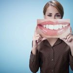 Brain Damage WARNING—No One Is Truly Safe! A woman holding a large image of a smiling mouth in front of her face
