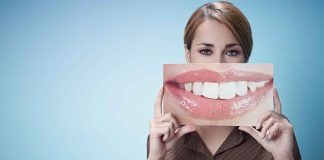 A woman holding a large image of a smiling mouth in front of her face