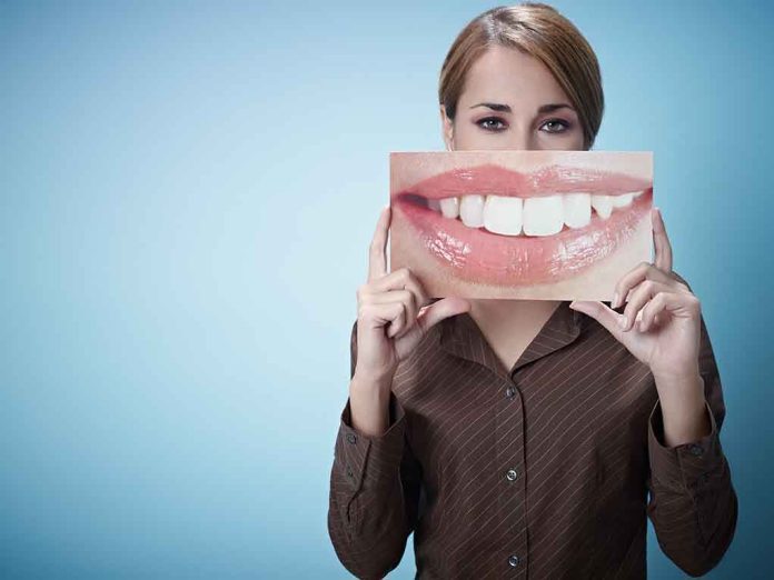shutterstock_66016204.jpg A woman holding a large image of a smiling mouth in front of her face
