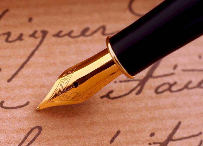 Close-up of a gold nib fountain pen resting on handwritten notes