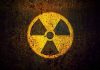 Yellow radiation warning symbol on rusty metal surface.