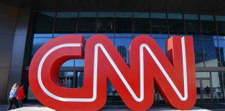 Large red CNN sign outside building entrance.