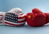 China’s Chokehold Strangles U.S. Defense USA and China boxing gloves facing each other.