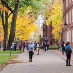 Colleges PANIC as Trump Begins Campus Crackdowns People walking on a college campus in autumn.