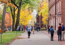 Colleges PANIC as Trump Begins Campus Crackdowns People walking on a college campus in autumn.
