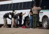 Border patrol officers investigating people near a bus.