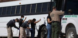 Border patrol officers investigating people near a bus.