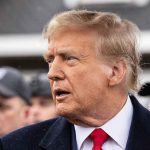 Trump Nigeria Story Just Fell Apart Man in suit and red tie speaking outside.