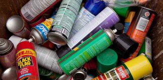 A pile of discarded spray cans in a garbage bin