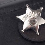 Liberal Justices Target Sheriffs—ICE Cooperation at Risk A silver sheriff badge resting on a black leather surface