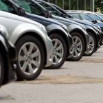 A row of parked black and silver cars in a dealership