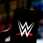 Hand holding phone displaying WWE logo.