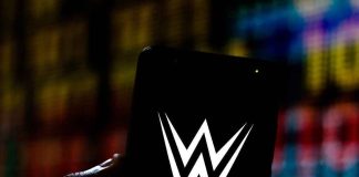 Hand holding phone displaying WWE logo.